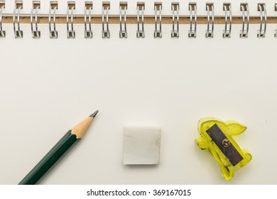 Pencil sharpener and an eraser on notebook 