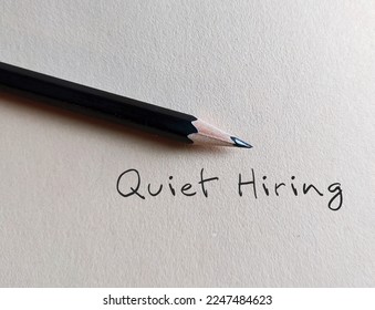 Pencil writing on beige background with handwritten text QUIET HIRING - HR buzz word of recruiting strategy, stand out employees who going above and beyond get more attention, money and praise  - Shutterstock ID 2247484623