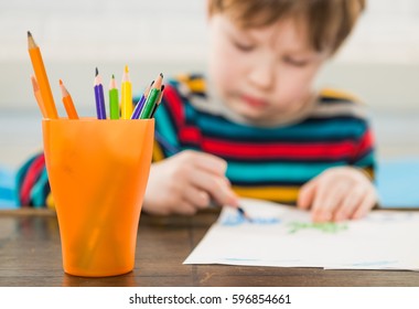 pencils in colorful jar with boy drawing on background