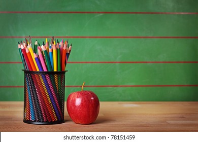 Pencils and red apple on table - Powered by Shutterstock