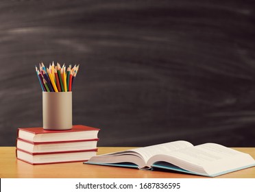 Pencils and study book on the desk on blackboard background