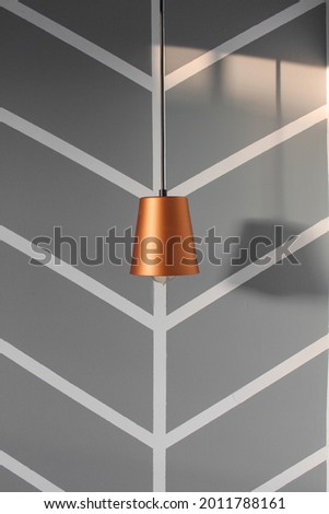 Pendent lamp with golden light and shadows on the wall. Interior design concept.