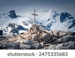 Penguins with chicks on rocks at memorial cross on Petermann Island, Antarctica.