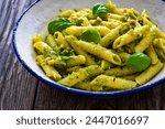 Penne with basil pesto sauce on wooden table 