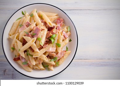 Penne Pasta With Bacon And Sundried Tomatoes. Alfredo Penne Pasta On White Plate On Wooden Table. Overhead, Horizontal