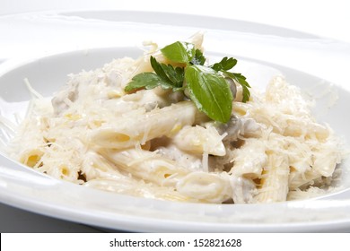 Penne Pasta With A Creamy Sauce With Parmesan Cheese And Basil On A White Plate On A White Background Isolated