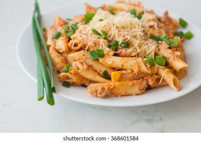 Penne pasta with healthy tuna fish, cheese and chopped scallion or spring onion leaves. Served on a white oval plate