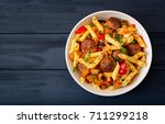 Penne pasta with meatballs in tomato sauce and vegetables in bowl. Top view. Flat lay