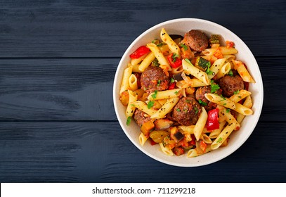 Penne pasta with meatballs in tomato sauce and vegetables in bowl. Top view. Flat lay - Shutterstock ID 711299218