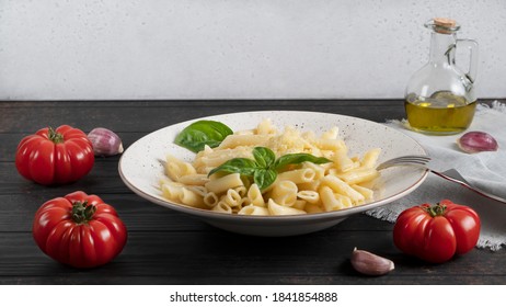 Penne Pasta On A White Plate With Tomatoes Peppercorns Garlic Olive Oil And Parmesan. Side View.