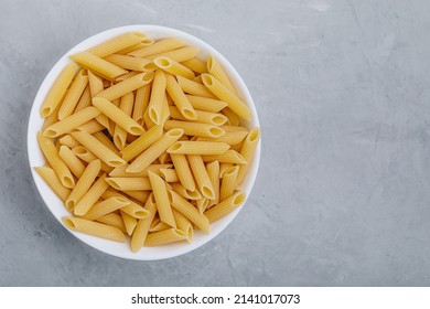 Penne pasta. Raw italian penne pasta on gray stone background, top view - Shutterstock ID 2141017073