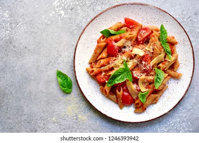 Penne pasta with tomato in red sauce on a white plate over light grey slate, stone or concrete background.Top view with copy space. - Shutterstock ID 1246393942