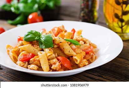 Penne Pasta In Tomato Sauce With Chicken, Tomatoes, Decorated With Basil On A Wooden Table. Italian Food. Pasta Bolognese.