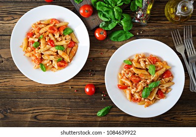 Penne Pasta In Tomato Sauce With Chicken, Tomatoes, Decorated With Basil On A Wooden Table. Italian Food. Pasta Bolognese. Top View