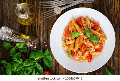 Penne Pasta In Tomato Sauce With Chicken, Tomatoes, Decorated With Basil On A Wooden Table. Italian Food. Pasta Bolognese. Top View