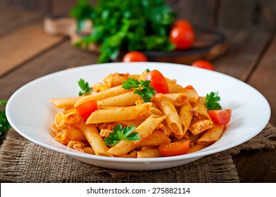 Penne pasta in tomato sauce with chicken, tomatoes decorated with parsley on a wooden background - Shutterstock ID 275882114