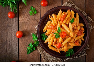 Penne pasta in tomato sauce with chicken, tomatoes decorated with parsley on a wooden table - Shutterstock ID 275882198