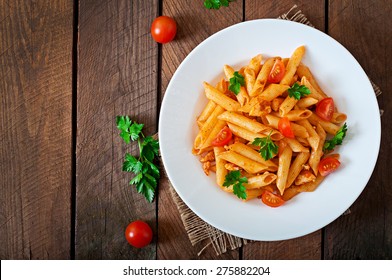 Penne pasta in tomato sauce with chicken, tomatoes decorated with parsley on a wooden background - Shutterstock ID 275882204