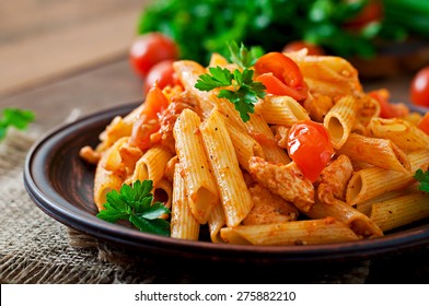 Penne pasta in tomato sauce with chicken, tomatoes decorated with parsley on a wooden table - Shutterstock ID 275882210