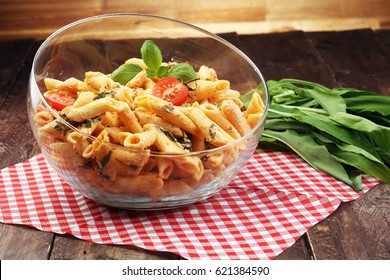 Penne Pasta In Tomato Sauce With Chicken, Tomatoes Decorated With Basil On A Wooden Table