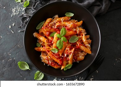 Penne pasta with tomato sauce, parmesan cheese and basil on dark background. Top view with copy space. - Shutterstock ID 1655672890