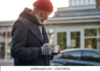 Penniless Man Collect Money For Shelter, Food. Male Desperately Look At Empty Cup From Coffee. Life Depends On Money. Homeless Person On Street