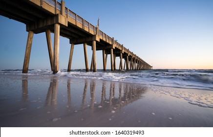 Pensacola beach pier during sunset with beautiful reflections on the sand in a vacation place in florida