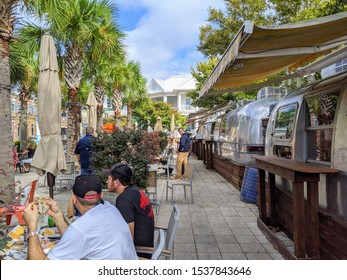 PENSACOLA, FLORIDA - OCTOBER 19, 2019:  Patrons dine al fresco next to Airstream food trucks under palm trees in downtown Pensacola