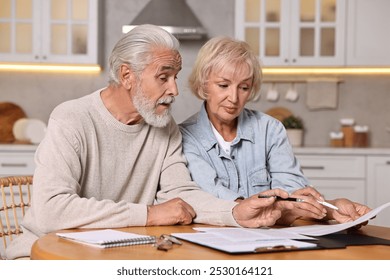 Pension savings. Senior couple planning budget at wooden table indoors - Powered by Shutterstock