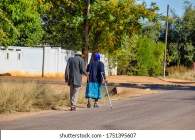 a pensioner couple with walking sticks strolling together on the side of the road