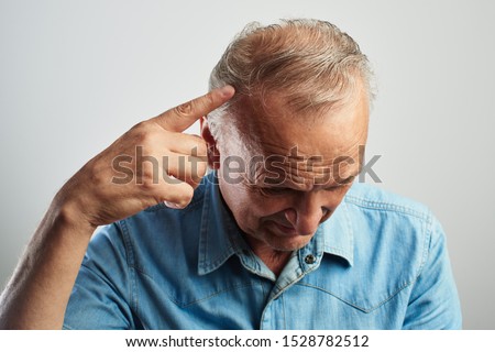Pensioner points a finger at a gray-haired balding head isolated on a white background. The problem of hair loss, androgenic alopecia