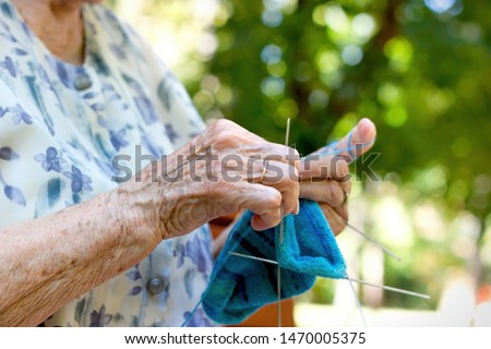 Pensioner woman knitting socks for her grandchildren, retiree lifestyle concept, enjoys in retirement