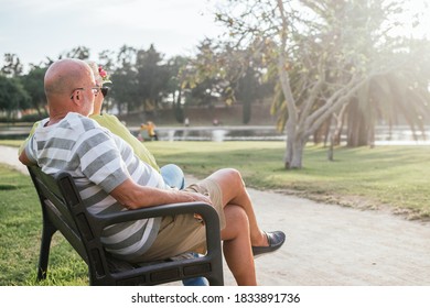 pensioners couple sitting on a park watching the sunset