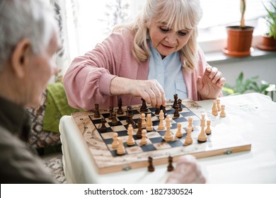 Pensioners pastime at senior home. Aged couple playing chess. Activities for seniors, elderly active lifestyle, older people time spending concept - Shutterstock ID 1827330524