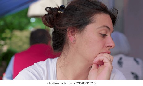 Pensive 30s woman close-up face gazing in the distance thinking while waiting for food at restaurant. contemplative expression of person, authentic and real life