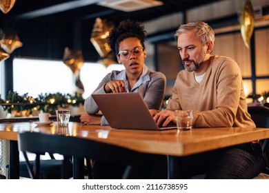 Pensive Adult Man, Helping His Work Partner With A Laptop, At A Bar.