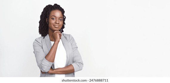 Pensive African American businesswoman in a grey blazer, standing against a white backdrop, with panoramic copy space for text. - Powered by Shutterstock