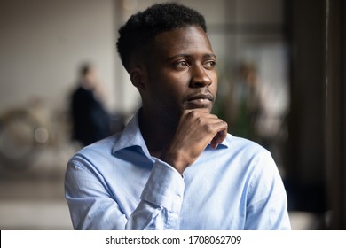 Pensive African American male employee look in distance thinking planning or visualizing, thoughtful biracial businessman lost in thoughts pondering over problem solution, business vision concept