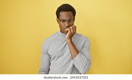 A pensive african american man in glasses stands against a yellow background, evoking thoughtful or worried concepts. - Powered by Shutterstock