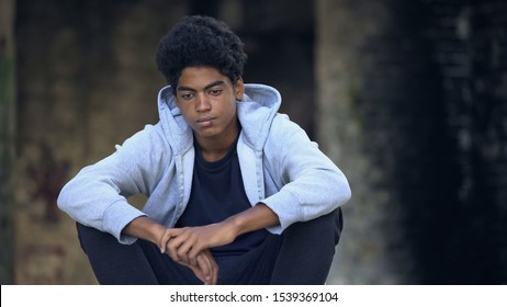 Pensive african american teenager with face wound sitting outdoors, bullying