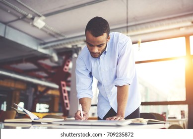Pensive afro merican architect drafting and making accountings concentrated on completing working task in office, skilled dark skinned male graphic designer in casual wear planning project  - Powered by Shutterstock