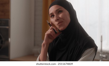 Pensive Arabian business woman freelancer in hijab Muslim girl female thoughtful businesswoman think ponder solution thinking come up with idea create happy smiling typing laptop at kitchen computer - Powered by Shutterstock