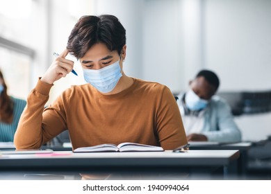 Pensive Asian Student In Mask Sitting At Desk In Class