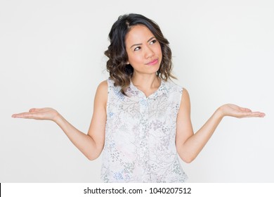 Pensive Asian woman spreading hands. Young lady presenting something with both hands or illustrating scale metaphor. Dilemma or hard choice concept - Shutterstock ID 1040207512