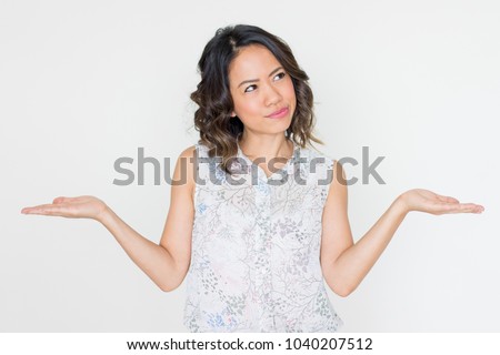 Pensive Asian woman spreading hands. Young lady presenting something with both hands or illustrating scale metaphor. Dilemma or hard choice concept
