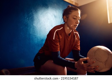 Pensive athletic woman with soccer ball in dressing room. Copy space. - Powered by Shutterstock