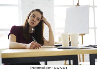 Pensive attractive young student concentrated on testing recalling knowledge to pass examination sitting at table in classroom, thoughtful female architect making project noting ideas during work - Powered by Shutterstock