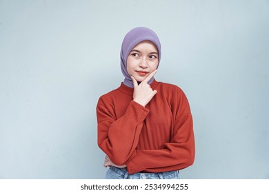 Pensive beautiful Asian woman in red sweater thinking about something and looking away isolated over white background. - Powered by Shutterstock