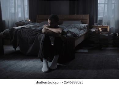 
Pensive black guy calms down with self hugging sitting on room floor 