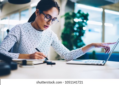Pensive business woman noting idea for startup planning from web page on laptop computer,professional administrative manager making accountings of income using app on netbook in office interior - Shutterstock ID 1051141721